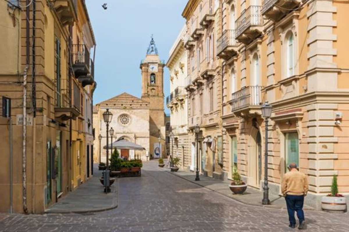 Scatto ravvicinato di un tavolo rustico con piatti tipici abruzzesi (brodetto, pallotte, ventricina, pizza scima) in una trattoria nel centro storico di Vasto; atmosfera conviviale
