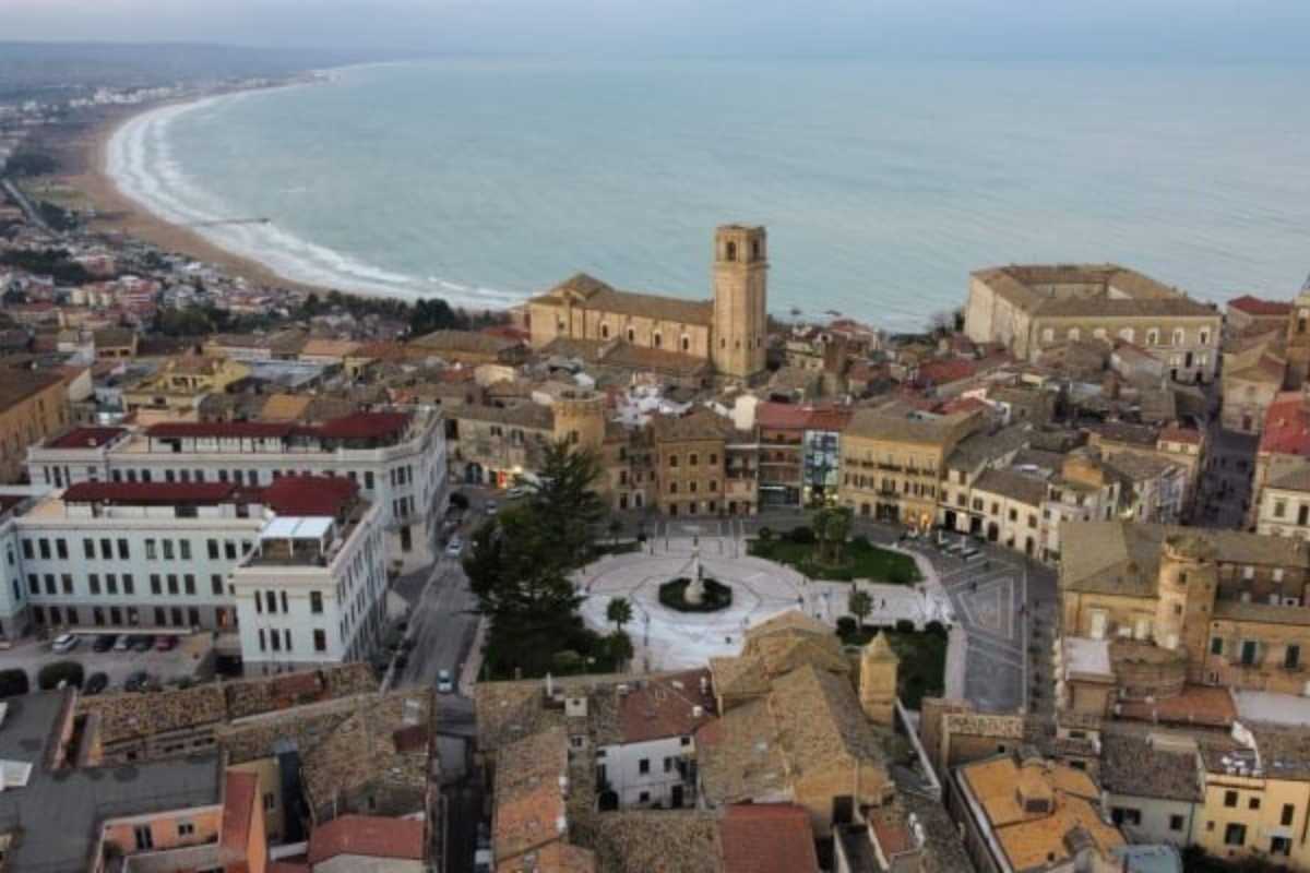 Panorama all’alba dal Belvedere di Vasto, con vista sulla costa e il centro storico. Atmosfera estiva, colori caldi, dettagli dei trabocchi in lontananza.