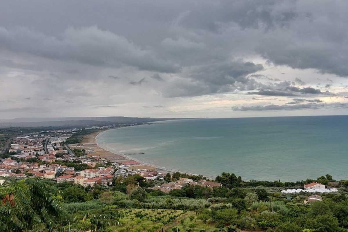 Spiaggia di Vasto Marina al mattino, bambini che giocano sulla sabbia, fondale basso, ombrelloni colorati, atmosfera familiare